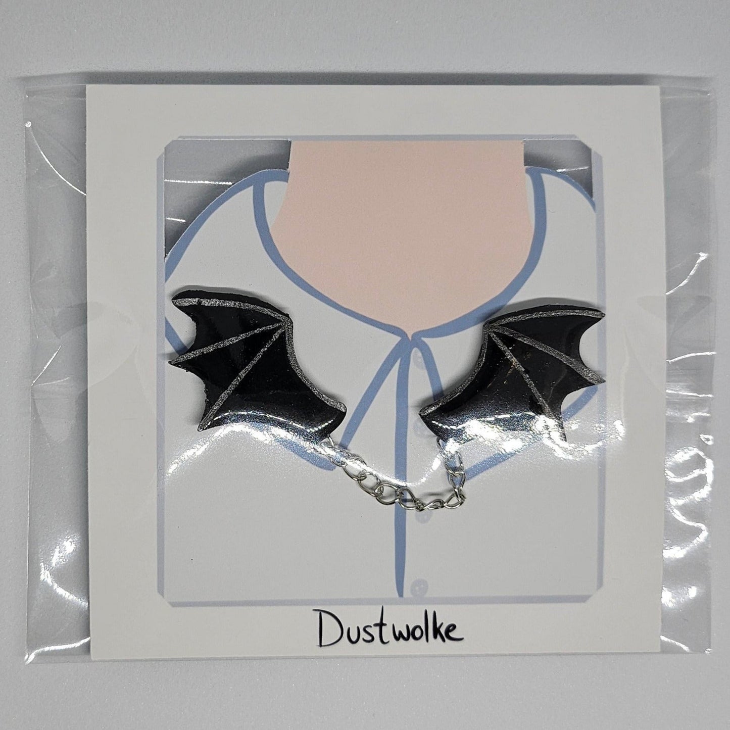 Handmade batwings double pin set in black and silver with connecting chain in packaging.