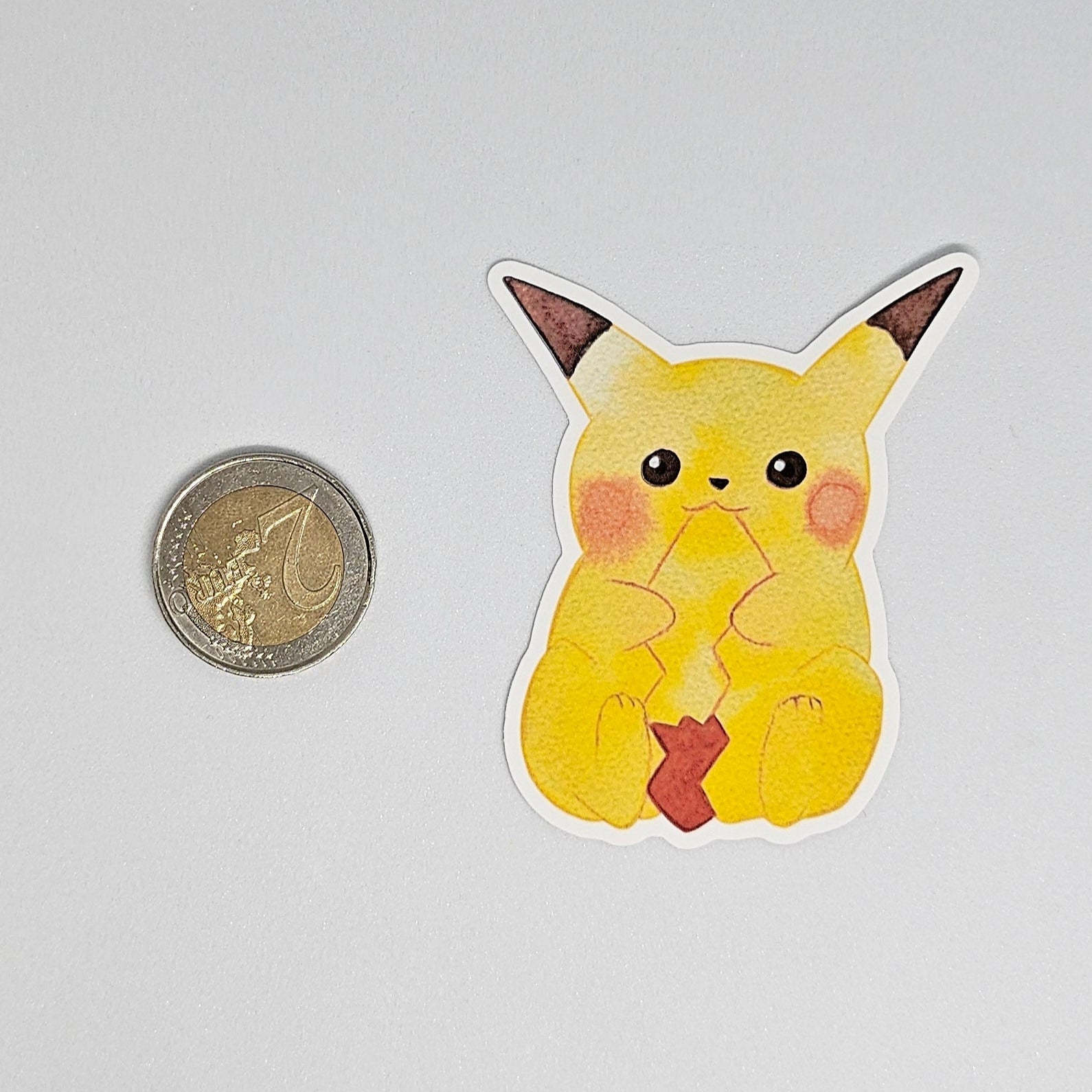 Pikachu sticker in comparison with a coin